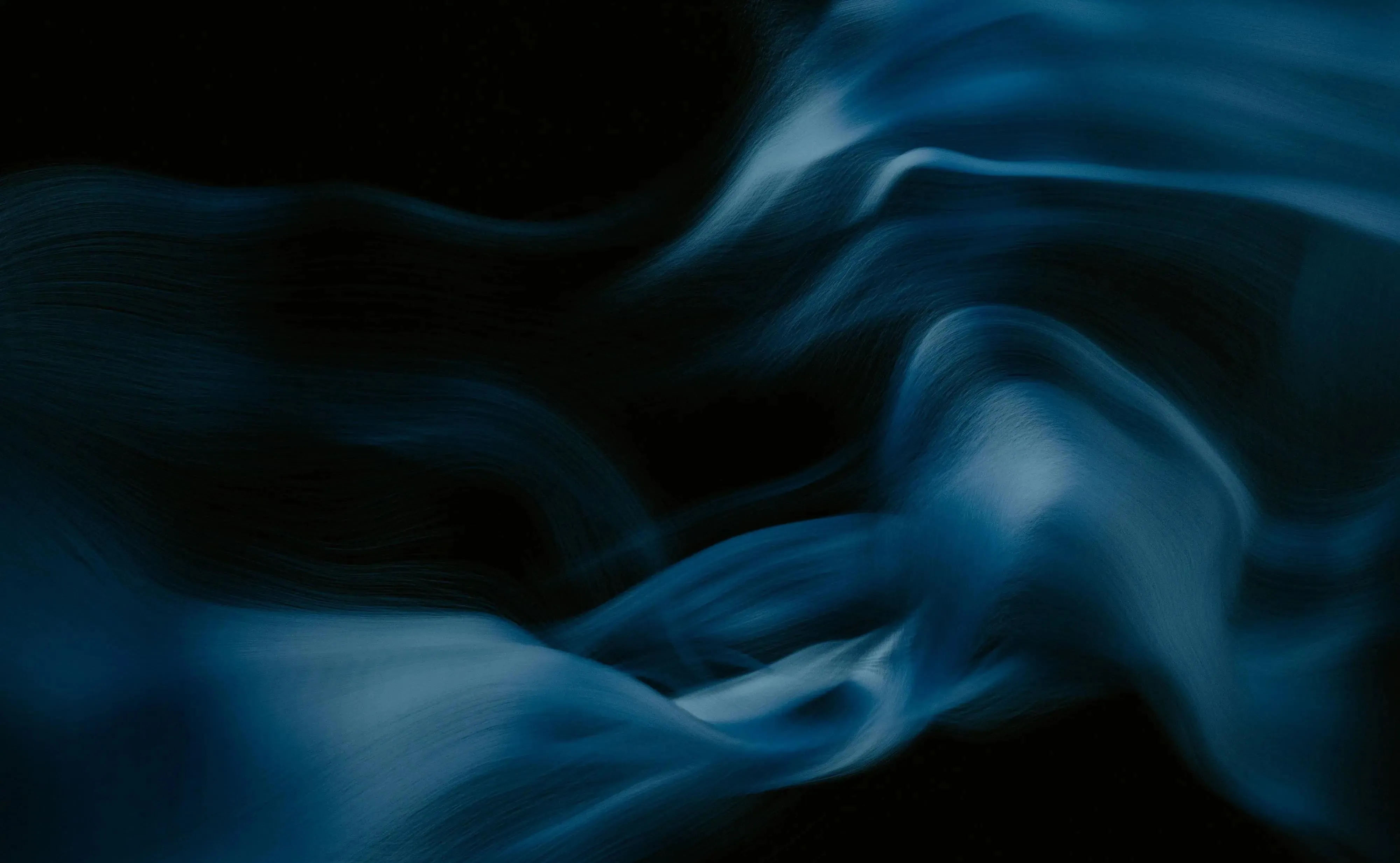 Abstract image of blue painterly whisps in dark space.